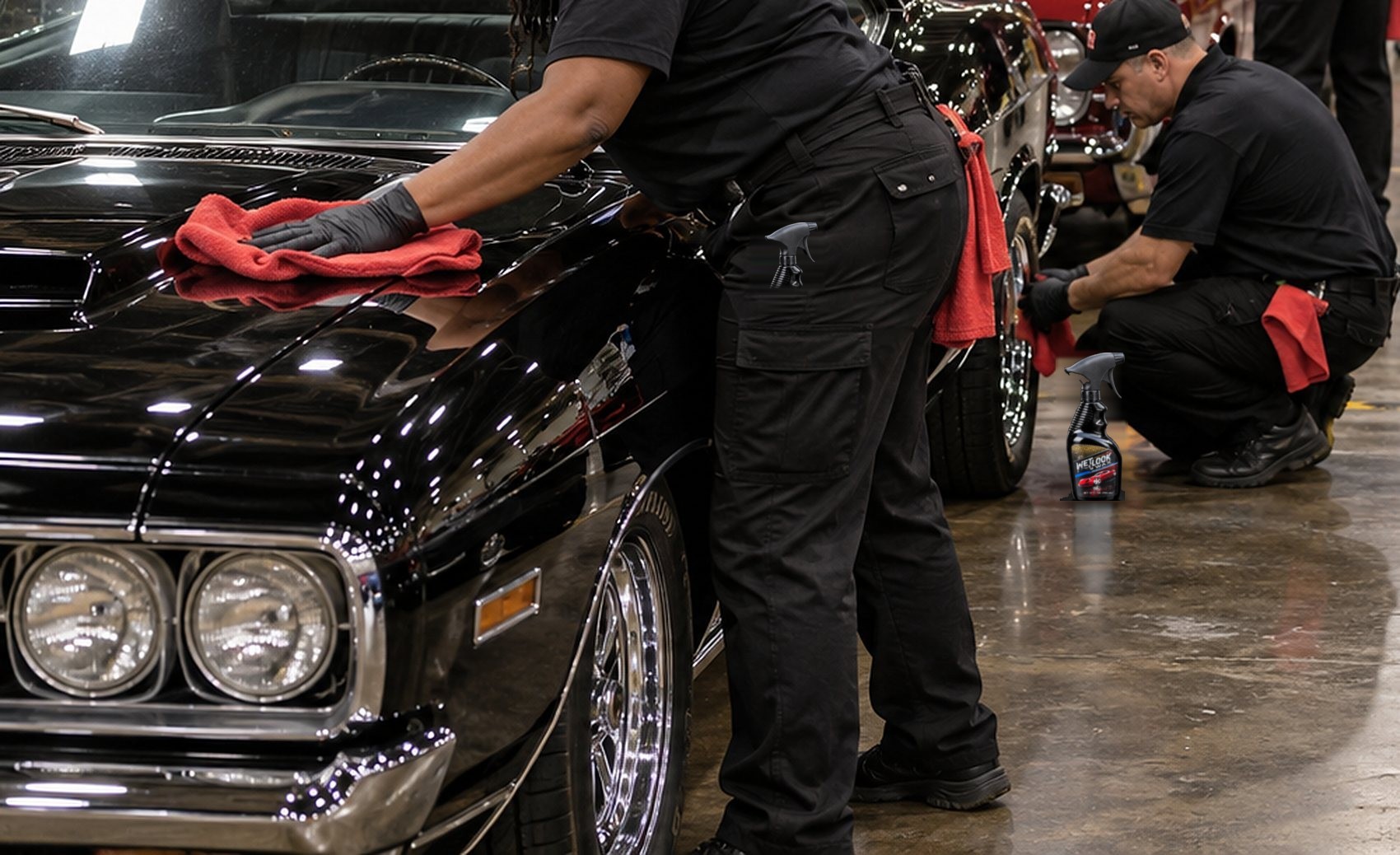 A gloved hand drying the hood of a black car on an exhibition hall floor