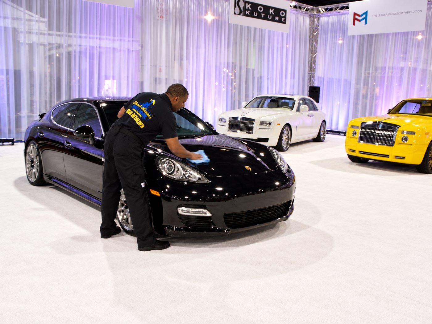 Chuck Mason drying the hood of a black sedan on a show floor