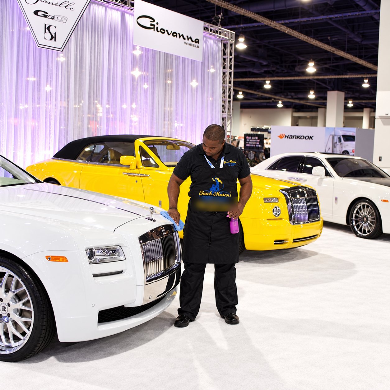 Chuck Mason standing among luxury vehicles on a show floor