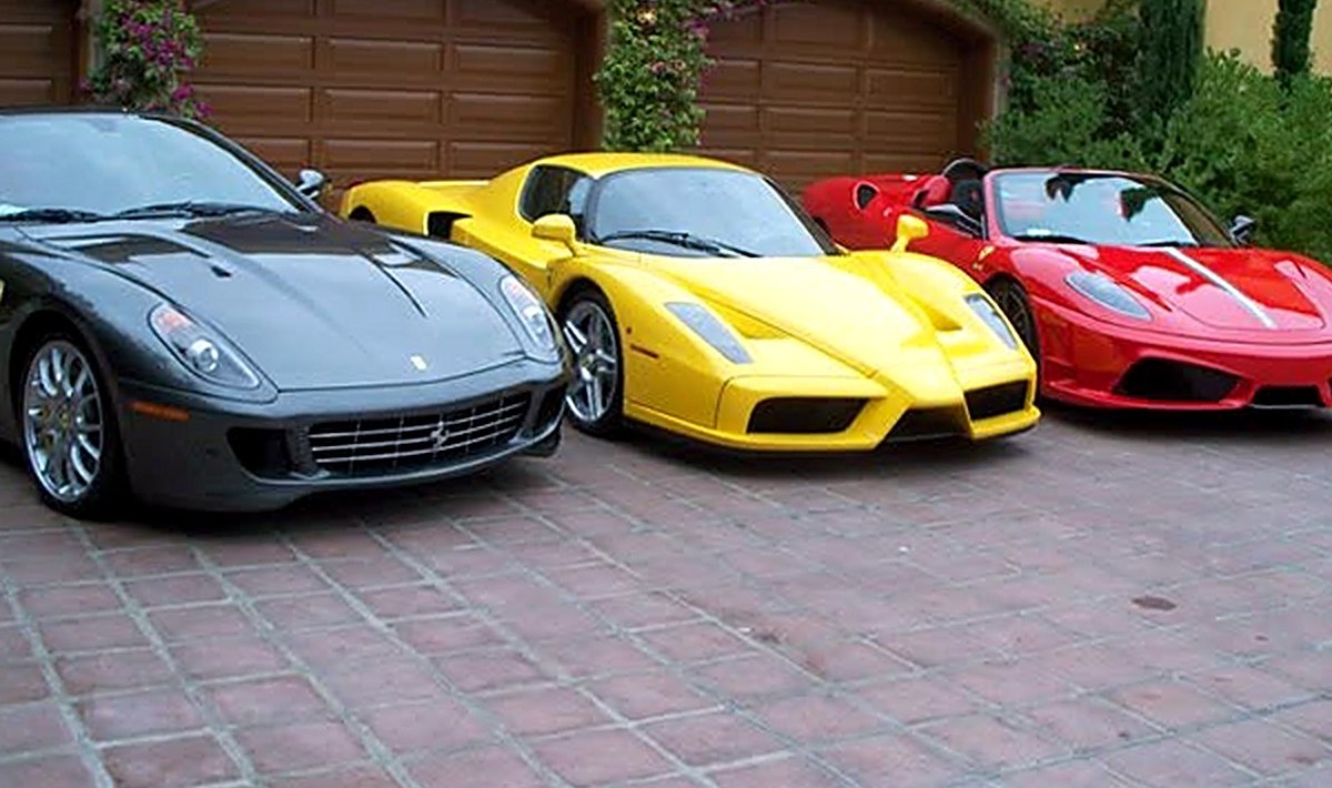 Three exotic cars, grey, yellow, and red, lined up at a private collection