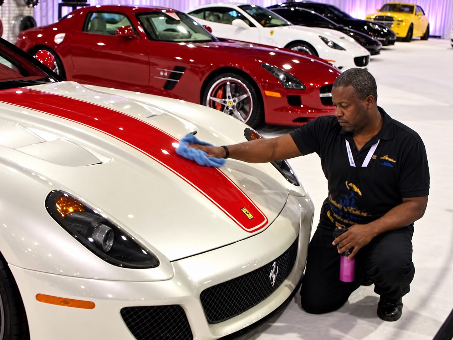 Chuck Mason hand-finishing the hood of a white Ferrari on a show floor