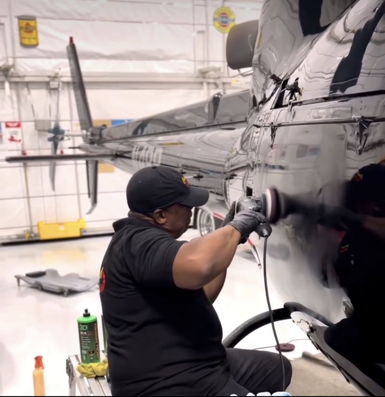 Chuck Mason polishing a helicopter fuselage in a hangar